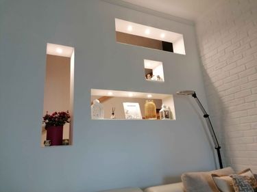 Встроенные светильники с люминесцентными лампами аккуратно установлены в нишах стены, обеспечивая равномерное освещение и создавая уютную атмосферу в интерьере.