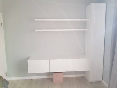 Установлены две белые полки на светло-серой стене, ровно закреплены, без видимых крепежей. Полки расположены параллельно, создавая аккуратный и современный вид интерьера.