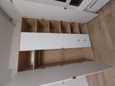 Собран вместительный шкаф с полками и ящиками, установлены дверцы, закреплены петли, добавлены ручки. Конструкция устойчива, готова к использованию, подходит для хранения вещей.