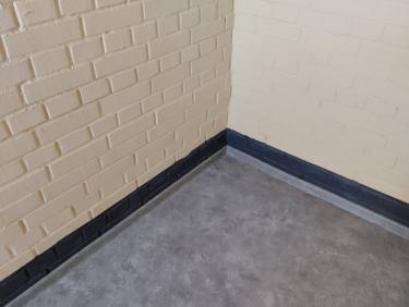 На ровное основание аккуратно уложено покрытие, тщательно подогнано по углам, без зазоров и складок. Завершена отделка плинтусами для эстетичного вида и надежной фиксации.