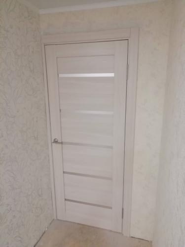 Установлена светлая межкомнатная дверь с одной створкой, аккуратно закреплена в проеме, добавлены петли и ручка, завершена отделка наличниками, обеспечена плавная работа.