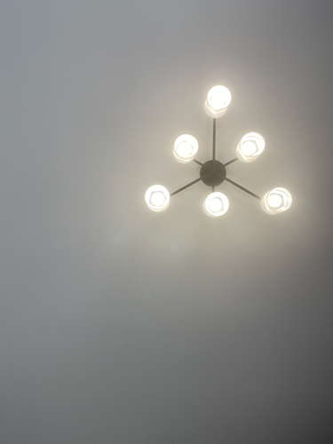 Люстра аккуратно закреплена на натяжной потолок, обеспечена надежная фиксация и подключение к электросети, светильник функционирует исправно, равномерно освещая пространство.