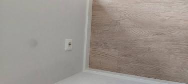 Установлен новый плинтус вдоль стены, аккуратно прилегающий к полу. Завершены все работы по подгонке и креплению, обеспечена ровная линия и плотное прилегание к поверхности.