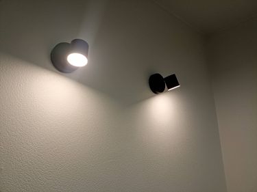 Изображены два установленных светильника на стене, освещающих пространство. Светильники закреплены на ровной поверхности, создавая мягкое освещение в помещении.