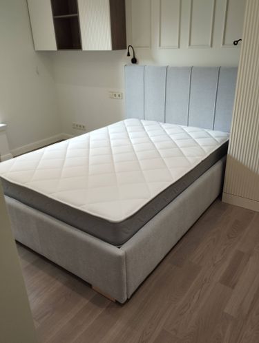 Собрана двуспальная кровать: установлены каркас, изголовье, закреплены ножки, уложен матрас. Все элементы соединены, проверена устойчивость, обеспечена надежность конструкции.