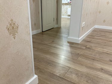 Уложено новое покрытие, ровно и аккуратно. Полы обновлены, стыки плотно прилегают, создавая гладкую поверхность. Завершено оформление плинтусами, гармонирующими с интерьером.