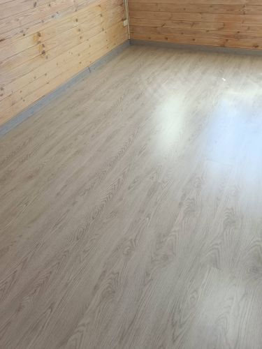 На ровное основание уложено ламинированное покрытие. Плашки аккуратно соединены, образуя гладкую поверхность. По периметру установлены плинтусы, завершив оформление пола.