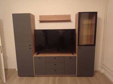 Установлена деревянная полка над телевизором между двумя шкафами. Работа выполнена аккуратно, конструкция надежно закреплена на стене, создавая гармоничный интерьер в комнате.