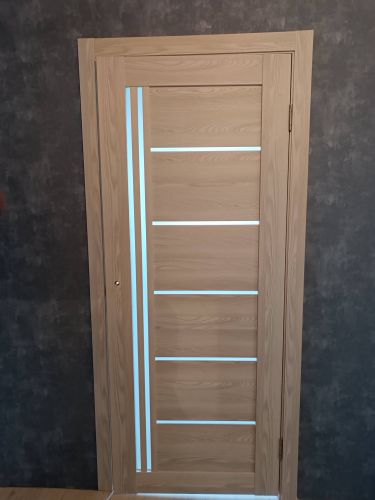 Установлена новая деревянная дверь с одной створкой, закреплены петли, врезан замок, отрегулированы зазоры, выполнена отделка наличниками, проверена плавность открывания и закрывания.