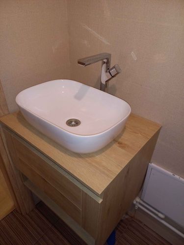 Установлена раковина на деревянную тумбу, подключен смеситель, обеспечена герметичность соединений, выполнено подключение к водопроводу и канализации, проверена функциональность.