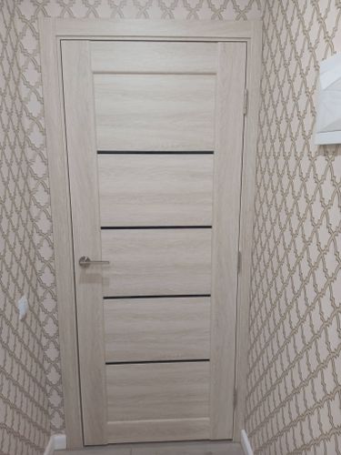 Установлена светлая створка с ручкой, петли закреплены, коробка выровнена, зазоры устранены, наличники подогнаны, конструкция надежно зафиксирована, внешний вид гармонирует с интерьером.