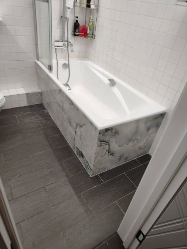 Ванная комната: уложен керамогранит на пол, облицован экран ванны, швы затерты, поверхность ровная, плитка серого оттенка, создающая стильный и современный вид помещения.