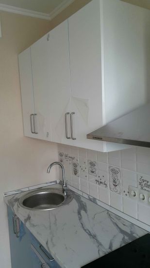 Установлены шкафы, закреплены фасады, смонтирована столешница из искусственного камня, врезана мойка, подключен смеситель, установлена вытяжка, оформлен фартук плиткой.