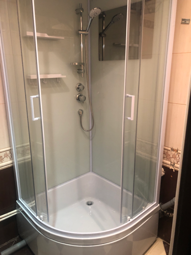 Установлена современная душевая конструкция: закреплены стеклянные панели, смонтирован поддон, подключены водопроводные шланги, установлены полки и душевой комплект.