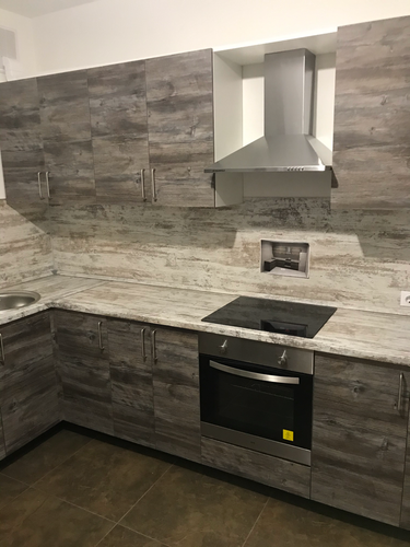 Установлены кухонные шкафы, смонтирована столешница, встроена варочная панель, подключена вытяжка. Завершена сборка и установка всех элементов, обеспечена функциональность и эстетика.