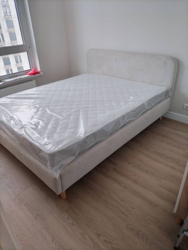 Собрана двуспальная кровать: установлены ножки, прикреплено изголовье, уложен матрас. Все детали надежно закреплены, конструкция устойчива, готова к использованию.