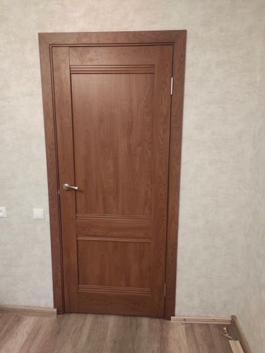 Установлена новая деревянная дверь, закреплены петли, врезана ручка, отрегулировано полотно, зафиксирован наличник, проверена плавность открывания и закрывания, устранены зазоры.