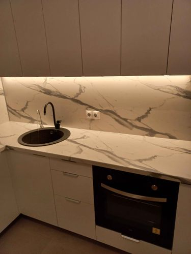 Установлены шкафы, закреплена столешница, вмонтирована мойка, подключены бытовые приборы, смонтирован фартук, проведена подсветка. Все элементы аккуратно собраны и выровнены.