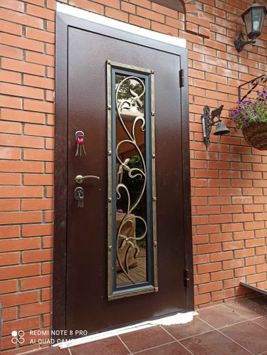 Установлена новая металлическая дверь с декоративной вставкой. Проведены работы по монтажу, выравниванию и закреплению конструкции. Обеспечена надежная фиксация и герметизация проема.