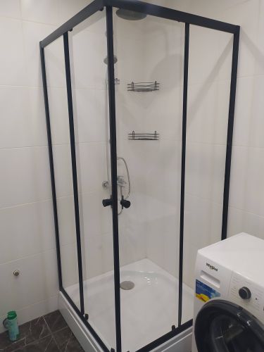 Установлена стеклянная конструкция с черными рамами, закреплены полки, подключен смеситель, герметично зафиксирован поддон, проверена работа слива, обеспечена надежная герметизация.