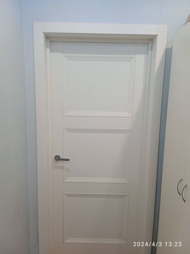 Установлена белая межкомнатная дверь с ручкой, выполнена подгонка и монтаж коробки, закреплены петли, обеспечена плавность закрывания, завершена отделка проема наличниками.