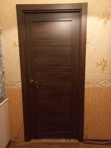 Установлена деревянная створка с ручкой, закреплены петли, выровнена коробка, добавлены наличники, выполнена подгонка по высоте и ширине, обеспечено плотное прилегание к проему.