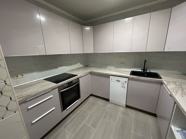 Установлены шкафы, закреплены фасады, смонтирована столешница, подключены бытовые приборы, врезана мойка, установлены розетки, проведены коммуникации, завершена отделка стен плиткой.