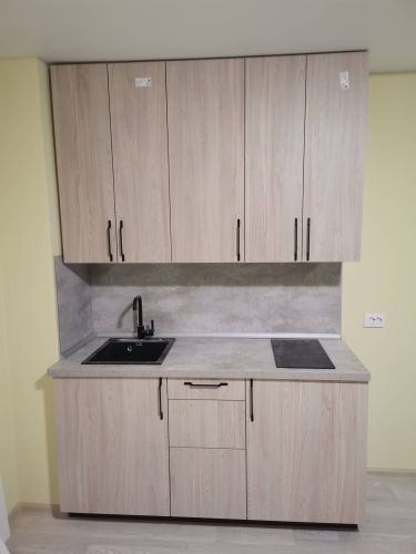 Установлены шкафы, закреплены фасады, смонтирована столешница, подключены раковина и варочная панель, установлены ручки, выполнена отделка стен.