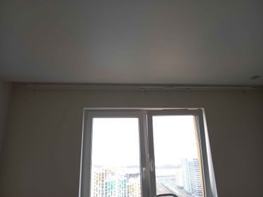 На потолке закреплён карниз, обеспечивающий надёжное крепление для штор. Установка завершена, конструкция выровнена и готова к использованию.