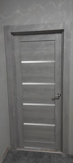 В деревянной двери аккуратно выполнено отверстие, установлена фурнитура, закреплена ручка. Все элементы надежно зафиксированы, обеспечивая плавное закрывание и открывание.