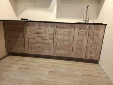 Установлены шкафы, закреплены фасады, смонтирована столешница, подключена мойка с краном, выровнены поверхности, установлены ручки, отрегулированы дверцы, завершена сборка.