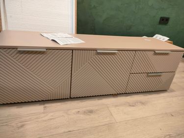 Собрана мебель с тремя ящиками и двумя дверцами. Установлены ручки, выровнены поверхности. Все элементы соединены, конструкция устойчива и готова к использованию.