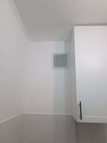 Завершена отделка стен: стеклохолст аккуратно наклеен, поверхность ровная, углы тщательно обработаны, создавая чистый и современный вид. Вентиляционная решетка и шкаф гармонично вписываются.