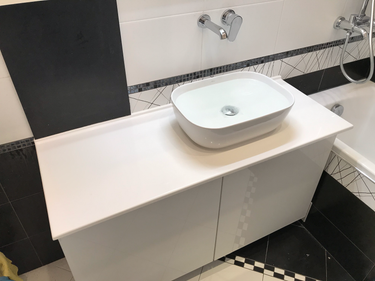 Установлена белая столешница из искусственного камня в ванной комнате, под раковину, с аккуратной подгонкой и надежной фиксацией, обеспечивающей долговечность и эстетичный вид.