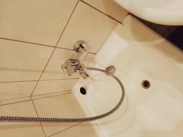 Изображение демонстрирует завершённую установку нового смесителя в ванной комнате, включая подключение душевого шланга и герметизацию стыков для предотвращения протечек.