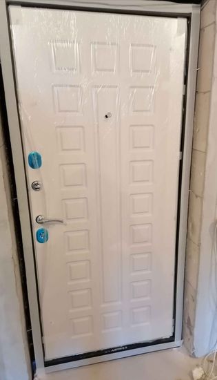 Установлена новая металлическая дверь, заменены замки, отрегулированы петли, обновлён уплотнитель, проверена герметичность. Завершён монтаж наличников, проведена финишная отделка.