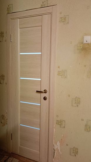 Установлена новая створка, закреплены петли, врезан замок, смонтирована ручка. Коробка выровнена, зазоры устранены, наличники установлены. Работа завершена аккуратно и качественно.