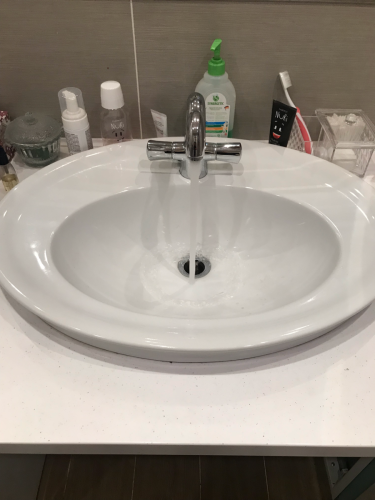 Изображение раковины с текущей водой. Работа завершена: устранено препятствие в сливе, восстановлен нормальный поток жидкости, обеспечена чистота и функциональность сантехники.