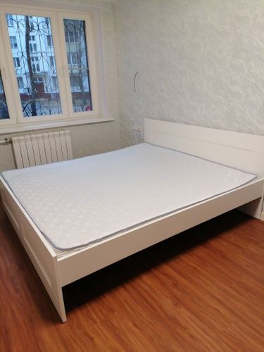 Собрана двуспальная кровать: установлены боковые панели, закреплено изголовье, уложено основание, проверена устойчивость конструкции. Установлен матрас, завершена проверка на прочность.