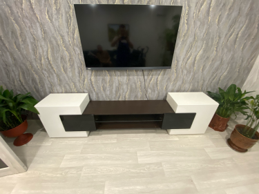 Собрана мебель: установлены боковые панели, закреплены полки, прикреплены дверцы, выровнена конструкция, проверена устойчивость, обеспечена функциональность, завершена установка.