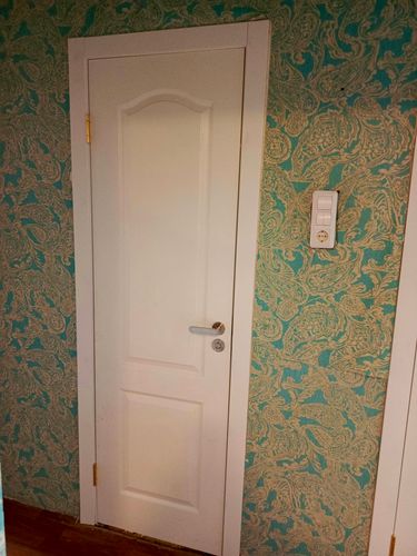 На деревянной двери установлено запорное устройство. Выполнены все необходимые отверстия и монтажные работы. Ручка и замок надежно закреплены, обеспечивая функциональность и эстетичность.