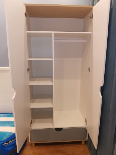 Собран шкаф с полками, дверцами, штангой для одежды и выдвижным ящиком. Установлены петли, закреплены элементы, выровнены поверхности, проверена устойчивость конструкции.