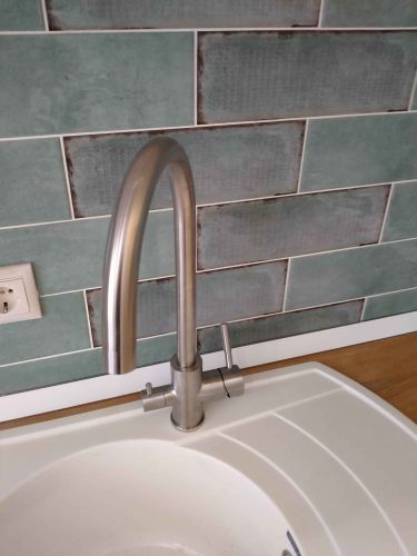 Изготовлено отверстие для установки мойки и смесителя, выполнены точные замеры и аккуратная подгонка, обеспечена плотная стыковка с плиткой, завершена установка сантехники.