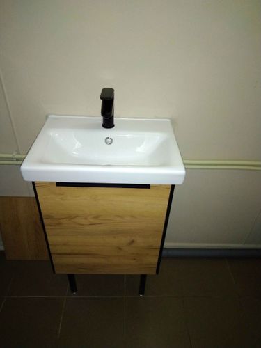 Изображение демонстрирует завершённую установку раковины с краном и тумбой. Зеркало отсутствует, но работа по монтажу сантехники выполнена аккуратно и качественно.