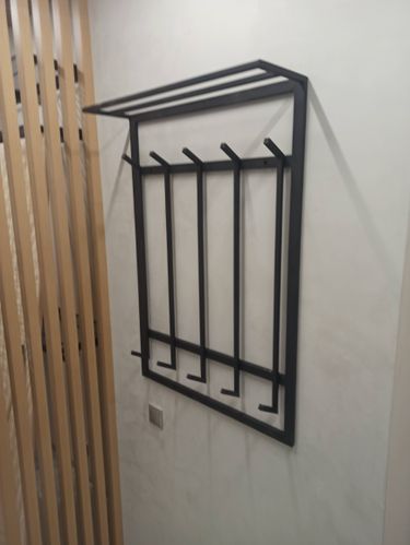 Закреплена металлическая конструкция на стене, обеспечивающая прочное крепление. Установлены крючки для одежды. Работа выполнена аккуратно, с точным соблюдением уровня и симметрии.