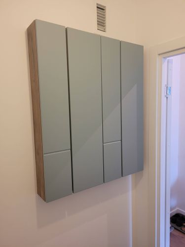 На стене закреплен шкаф с дверцами, выполнен монтаж, подключение к сети, проверена работоспособность. Устройство надежно закреплено, обеспечена безопасность эксплуатации.