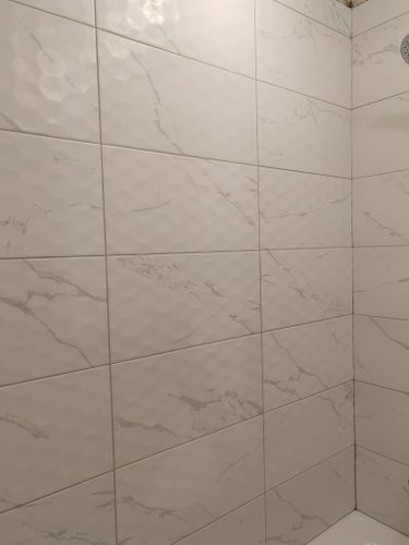 На стенах ровно уложена керамическая плитка с мраморным узором, швы аккуратно затерты, поверхность гладкая, без дефектов, создавая эстетичный и современный вид помещения.