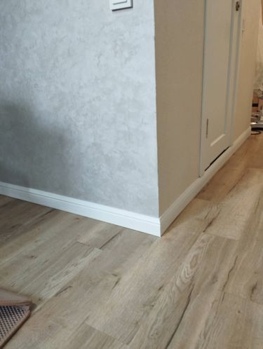 Установлен скрытый плинтус, аккуратно интегрированный в стену. Завершена отделка, обеспечивающая плавный переход между полом и стеной, создавая современный и эстетичный вид интерьера.