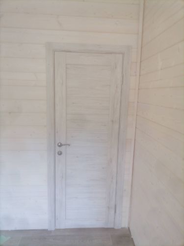 Установлена светлая дверь с ручкой и петлями. Коробка закреплена, створка ровно висит, плотно прилегает. Завершены работы по монтажу, обеспечена функциональность и эстетика.