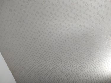 На стену аккуратно наклеен стеклохолст с мелким узором. Поверхность ровная, без видимых швов и пузырей, создаёт стильный и современный вид в интерьере.